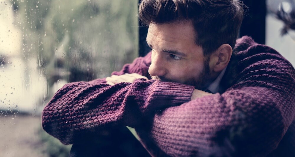 Man w/ alcohol addiction, sad & gazing out a rainy window