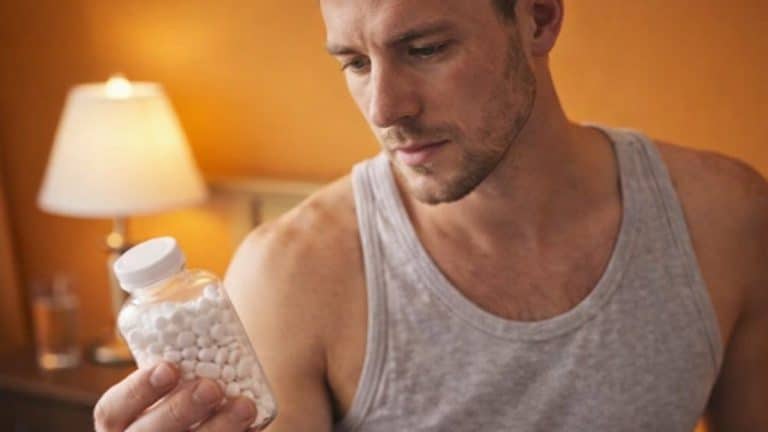 A man reading a pill bottle wondering if he can take ibuprofen and alcohol