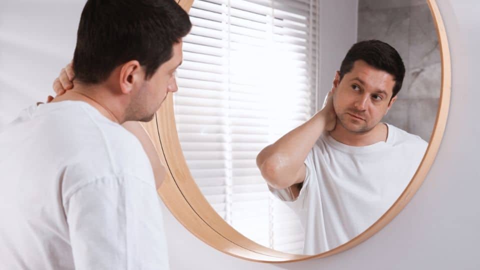 a man looks into a mirror while considering how bipolar and alcohol affect each other