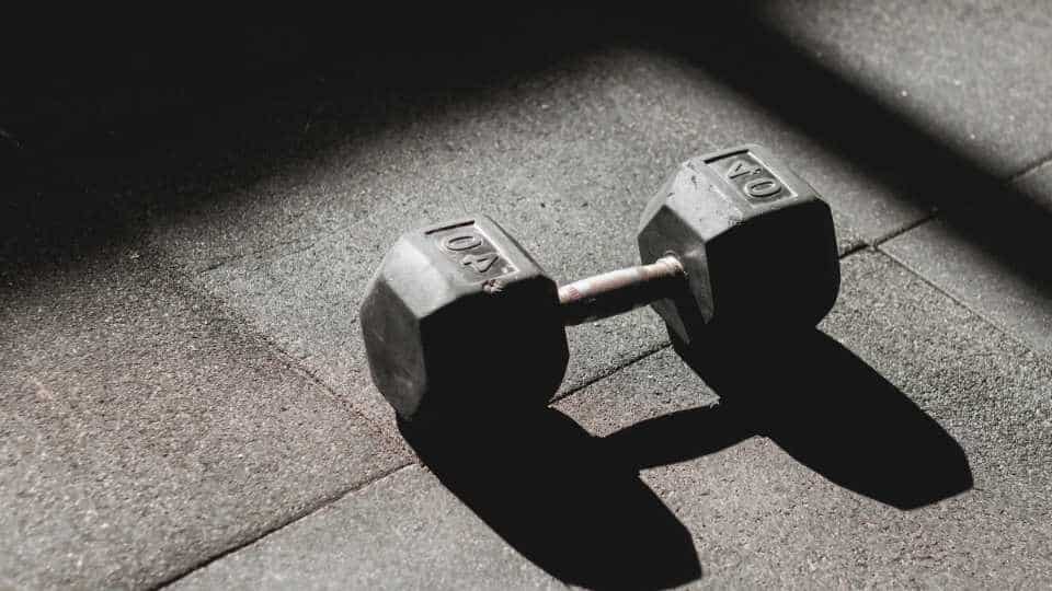 a dumbbell sits on the ground in shadow representing how alcohol affects muscle growth